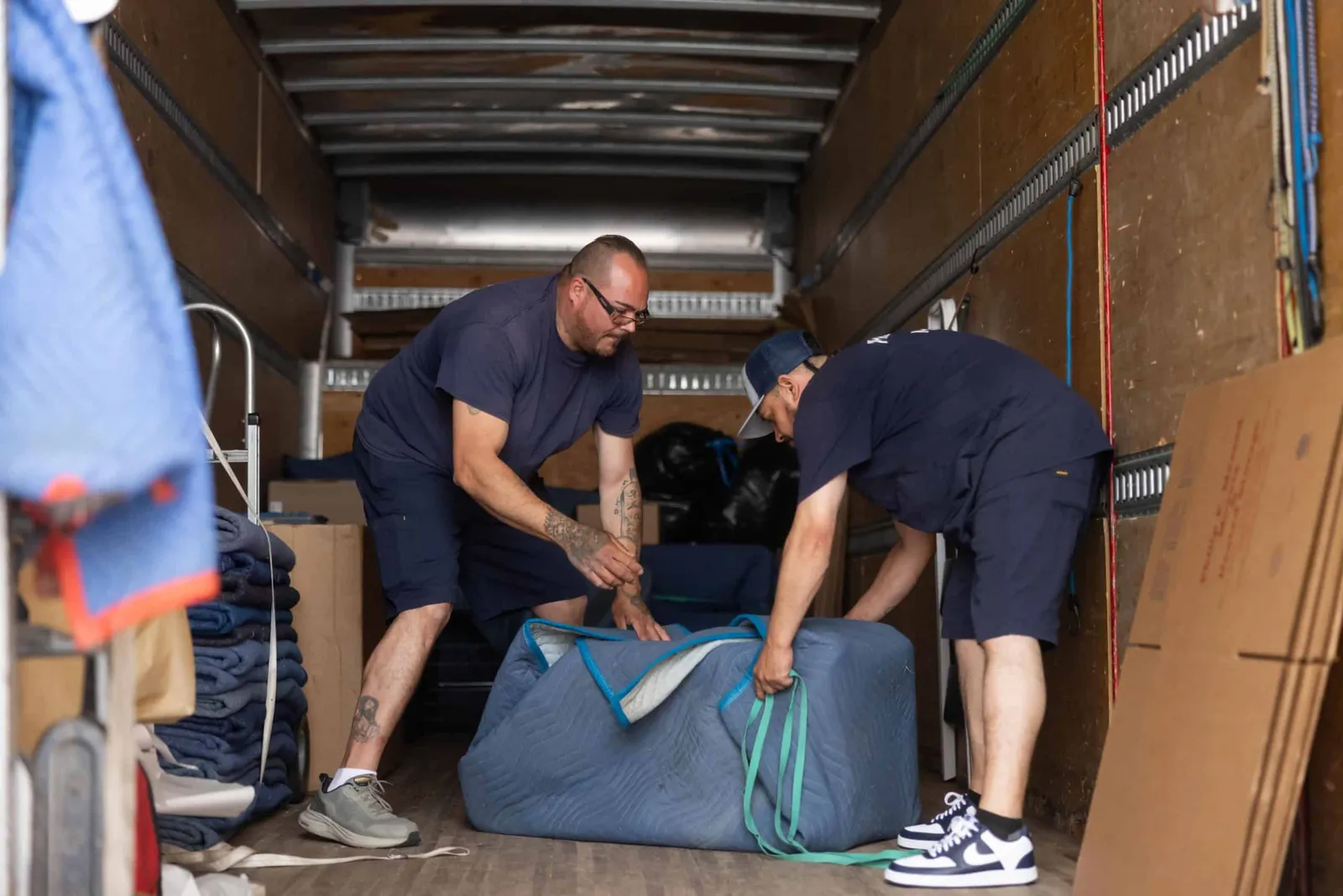 Two men unloading a large piece of furniture from a moving truck.
