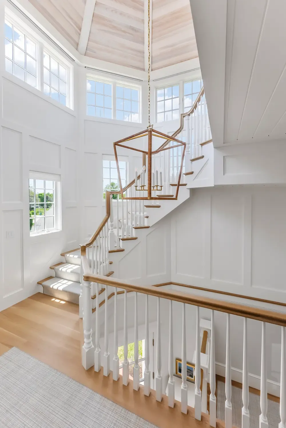 Bright sunlit staircase landing with white railings and a large decorative light