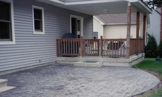 Gray stamped concrete curved patio with deck