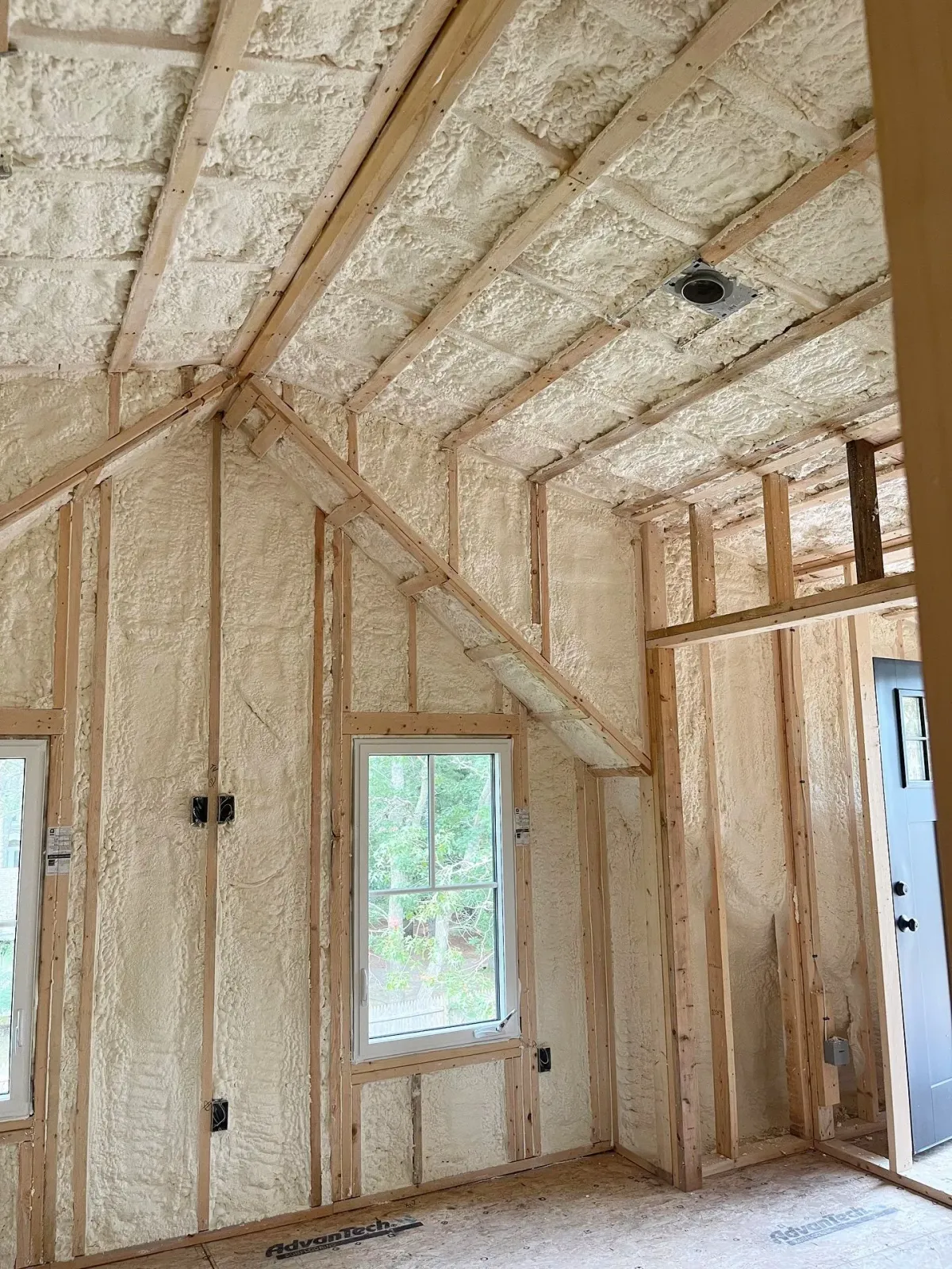 Interior of a building under construction with spray foam insulation in walls and ceiling.