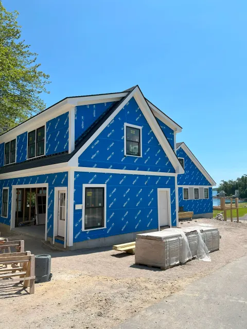 New home construction wrapped in blue Blueskin weather barrier with black-framed windows installed.