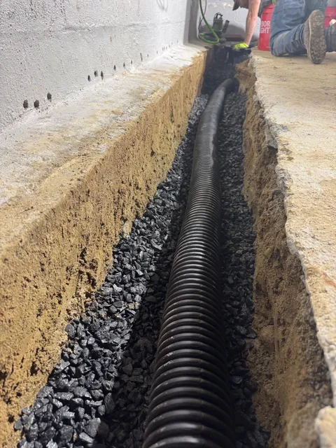 Interior perimeter drain pipe set in stone before the floor is patched