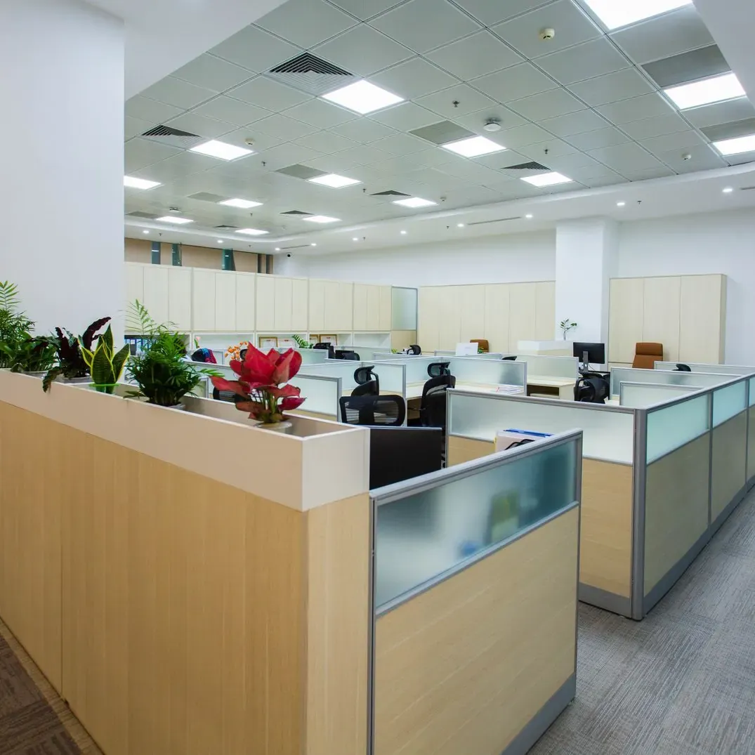 Open plan office floor with cubicle partitions, desks and potted plants