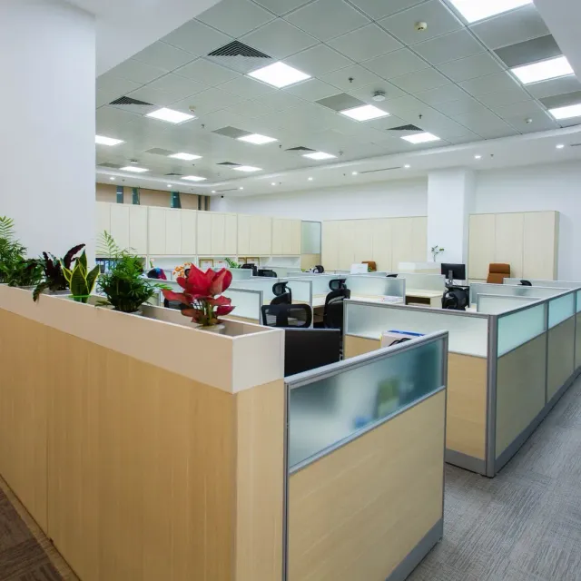 Open plan office floor with cubicle partitions, desks and potted plants