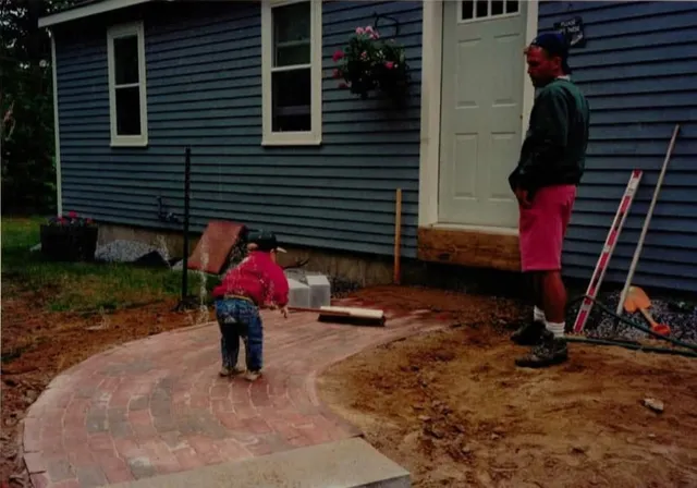 A skilled technician carefully setting stones for a curved garden path in New Hampshire.