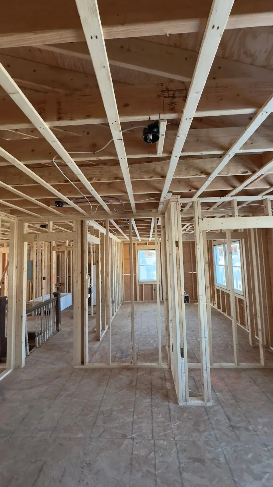 Interior of a house under construction; wooden framing for walls, ceiling, and floor are visible.
