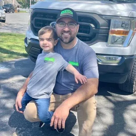 A man and a child seated together in front of a truck, sharing a moment of connection and joy.