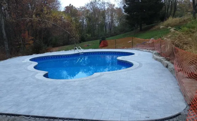 A large swimming pool is surrounded by a concrete patio.