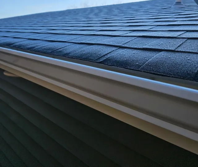 A white gutter with a black roof in the background