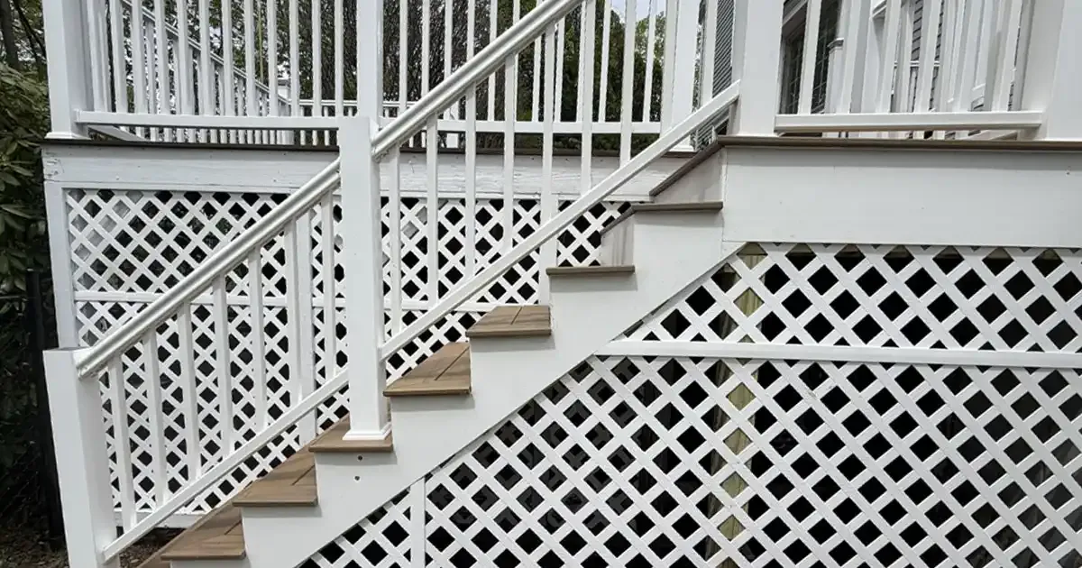 Rebuilt deck staircase with composite stair treads, white PVC railings, and white lattice skirting