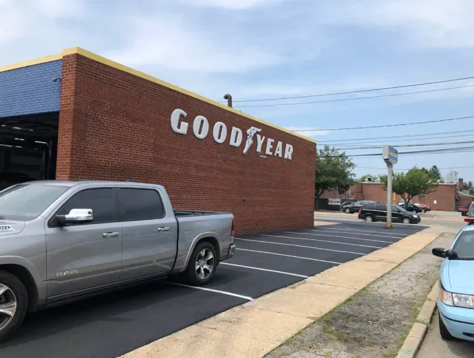 Goodyear tire shop exterior with parked pickup trucks on a sunny street corner