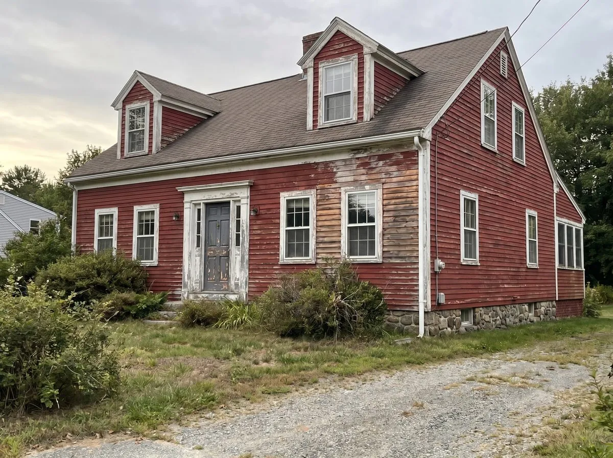 Weathered Cape Cod home with peeling red paint in Litchfield NH — before exterior repaint