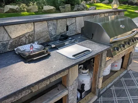 Outdoor kitchen with stone counter, grill, and cooking area