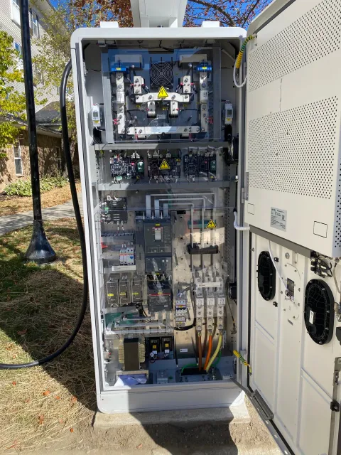 Open electrical or control cabinet with various electronic components, circuit boards, wiring, and cooling fans visible inside.