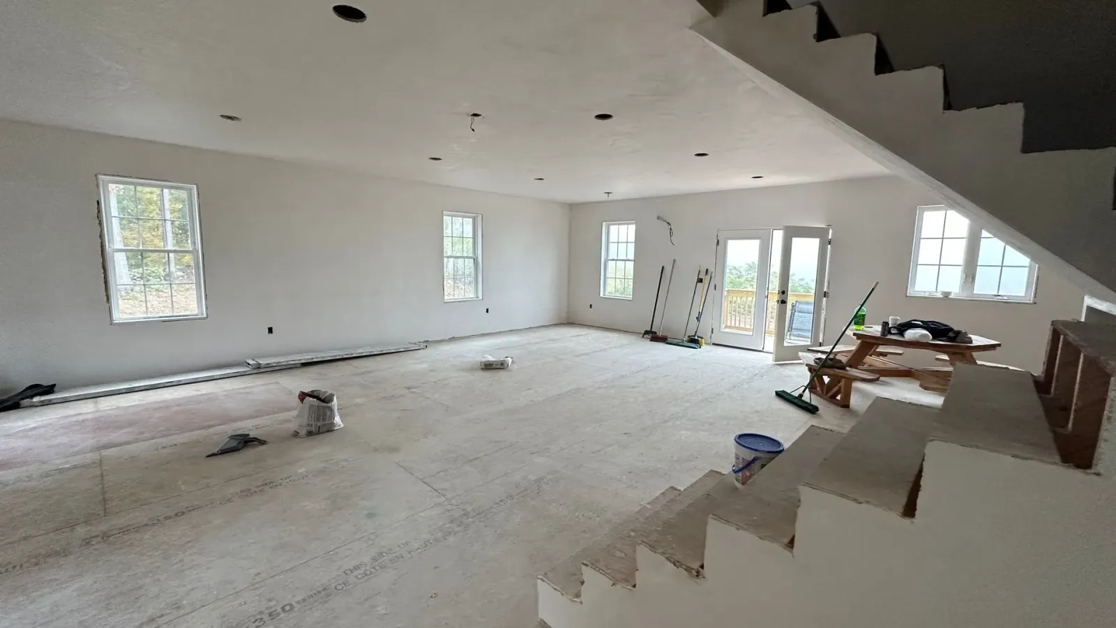 A large empty room with stairs and a lot of windows.
