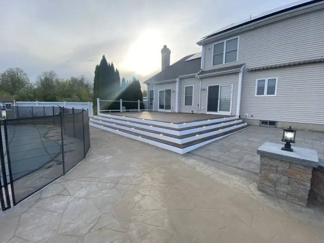 beige-house-with-modern-raised-deck-led-step-lights-and-stone-patio.webp