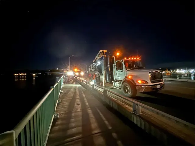 A truck is driving on a bridge at night.