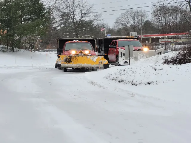 Two snow plows are driving down a snowy road.