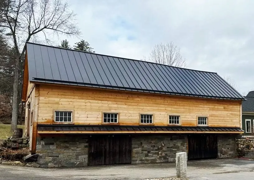 Black standing seam metal roof installed on a New Hampshire barn for long-lasting durability.