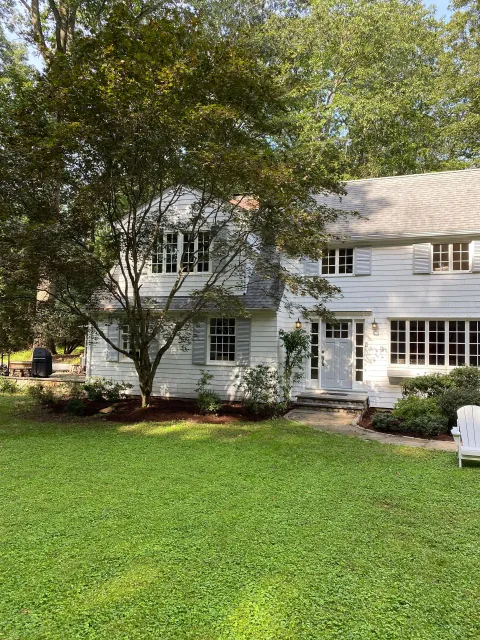A large white house with a lush green lawn in front of it.