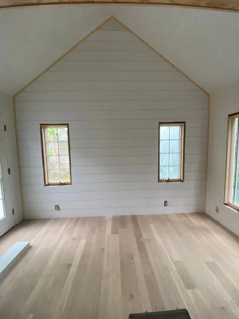 An empty room with a vaulted ceiling and wooden floors
