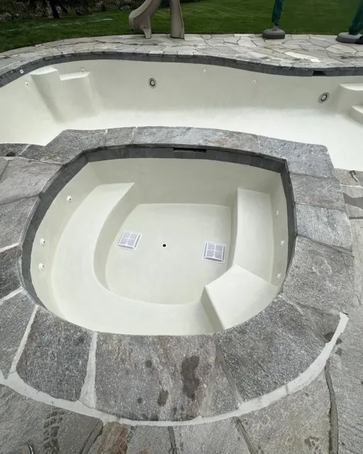 A swimming pool with a jacuzzi in the middle of it