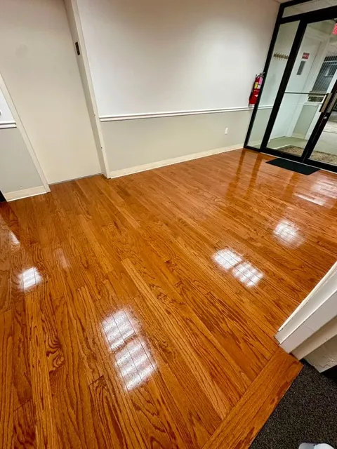A polished hardwood lobby floor beside glass entrance doors