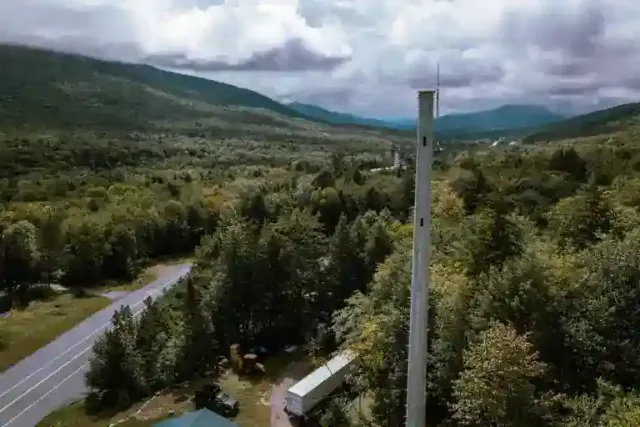 Aerial view of a highway passing through a forested valley with mountains in the background.