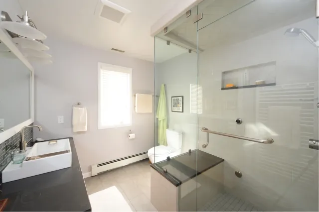 A renovated bathroom. New glass shower, basin, and toilet