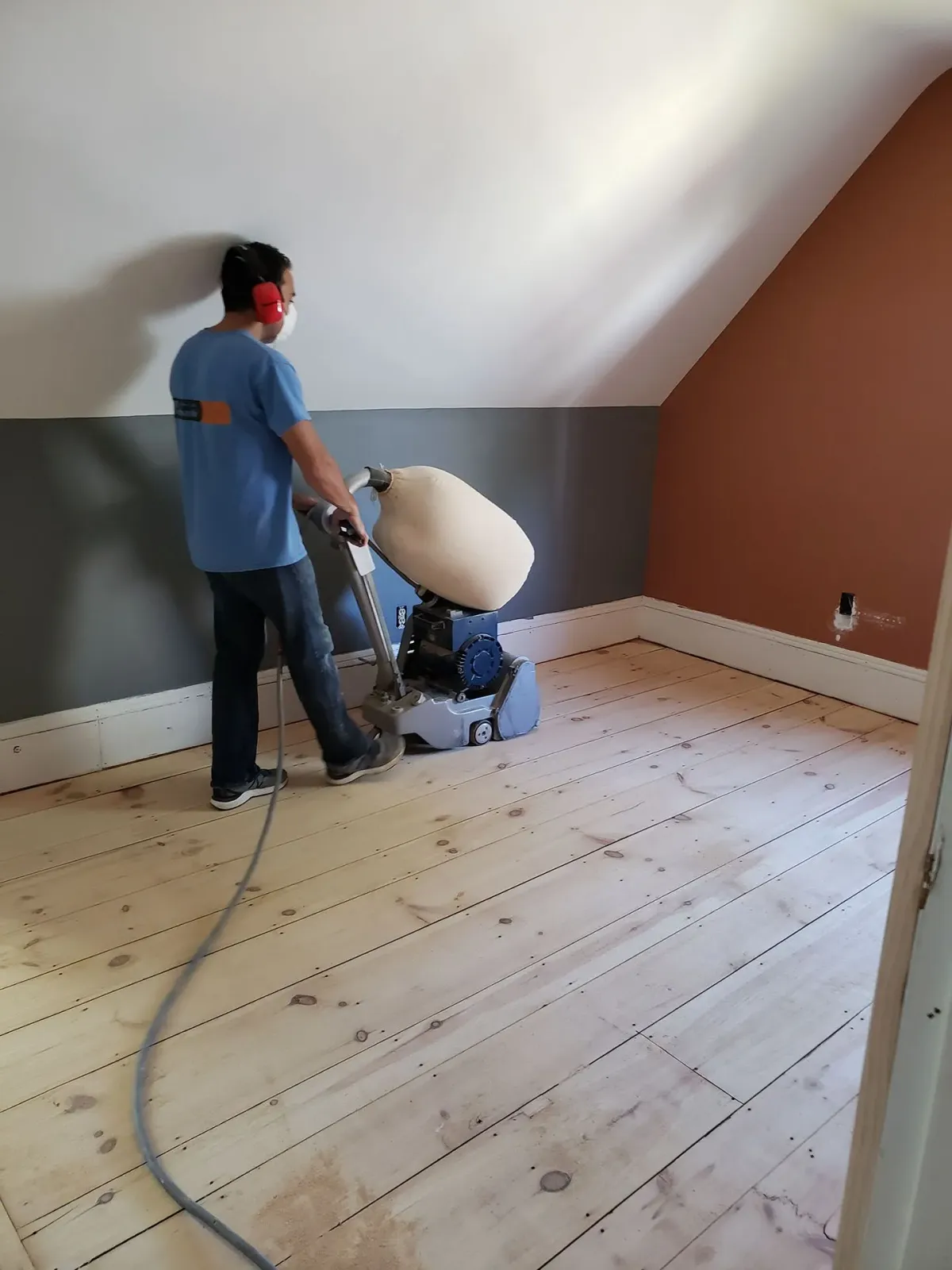 A man is sanding a wooden floor with a machine