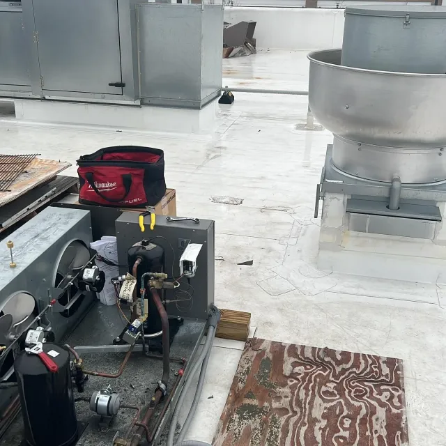 A red bag is sitting on top of a machine on a roof.