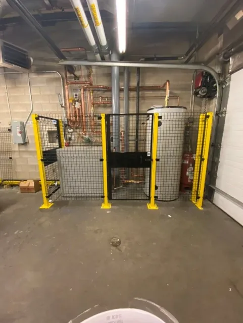 Yellow and black safety barriers around equipment in an industrial basement setting.