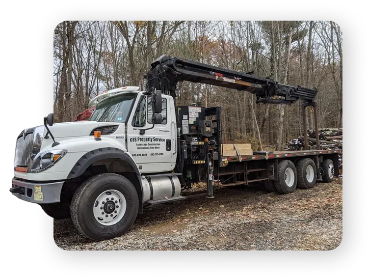 A white truck with a crane, branded with "CES Property Service," parked on a construction site.
