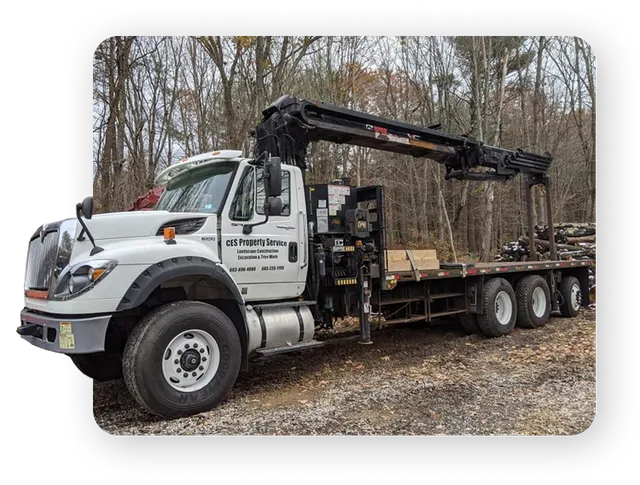 A white truck with a crane, branded with "CES Property Service," parked on a construction site.