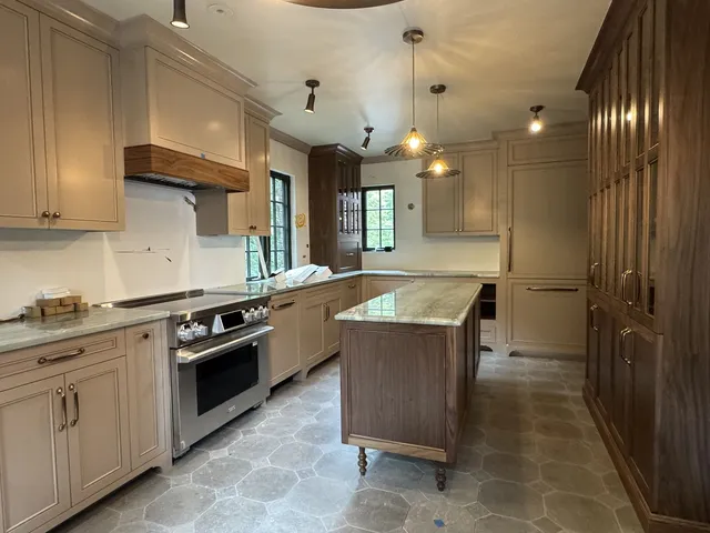 Custom taupe kitchen cabinets with wood hood and walnut island