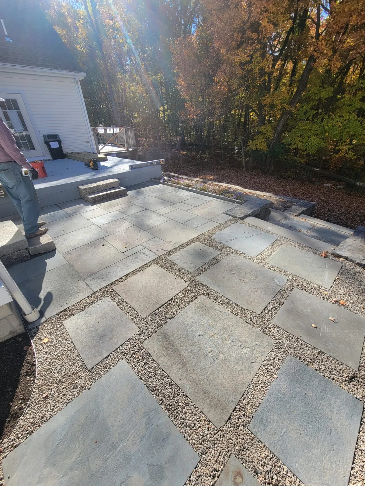 A man standing on top of a patio with gravel.