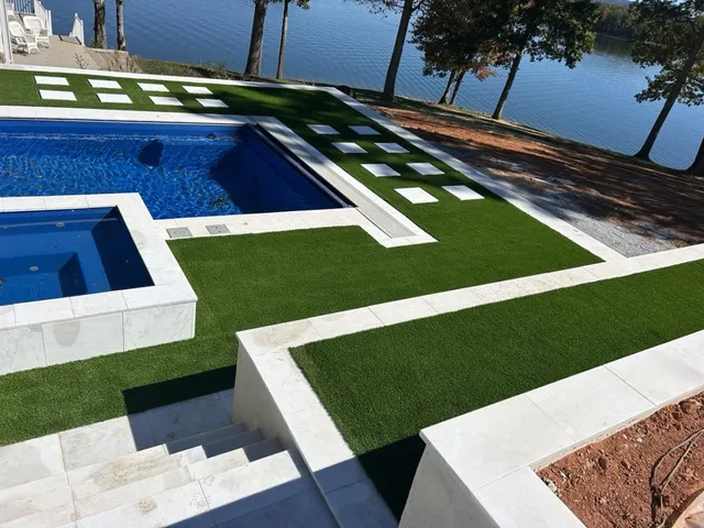 Elegant pool and spa installation with Global Syn-Turf Cool Blue Lime artificial grass and lakefront view in Wilmington, NC.