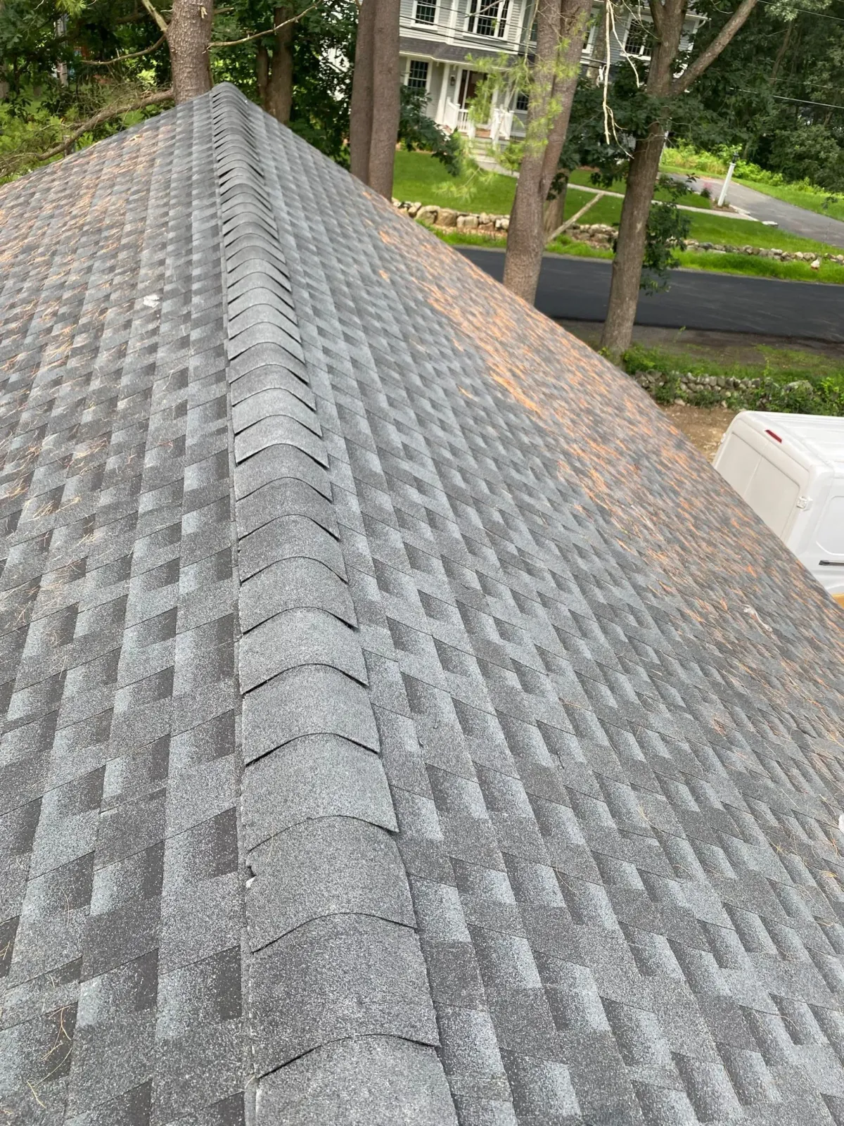 A close-up of a roof with a house in the background.