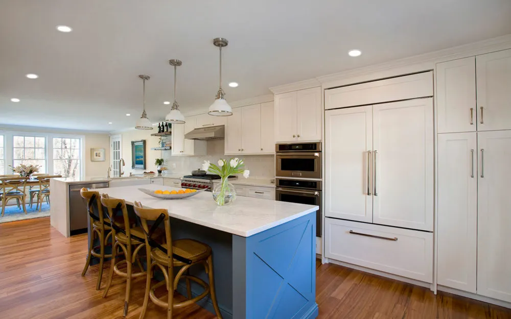 Bright kitchen with white cabinets, blue island, tulips, and stainless appliances – Woodland Builders, South Shore MA.