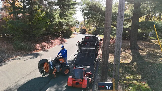 A man is driving an atv down a road next to a mailbox with the number 17 on it
