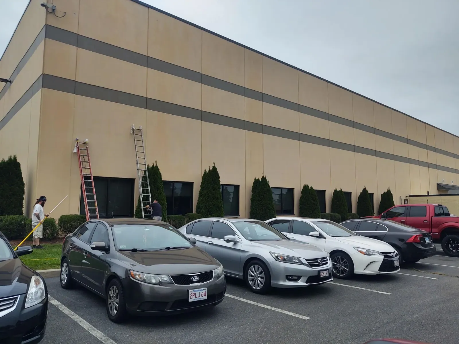 A row of cars are parked in front of a large building
