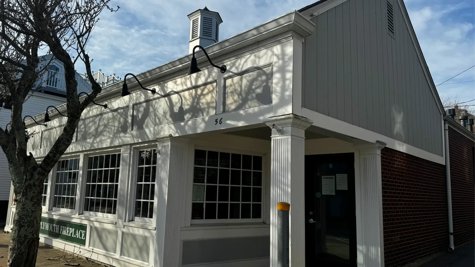 The Plymouth Fireplace storefront at 56 Court Street: white clapboard, fluted pilasters, divided-light windows, and a cupola