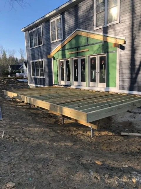 Pressure-treated deck platform framed on steel piers in front of the French doors