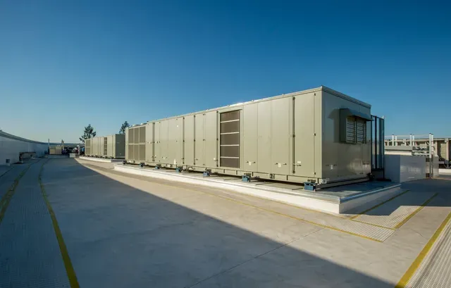 Exterior view of industrial air conditioning units on a rooftop under a clear blue sky.