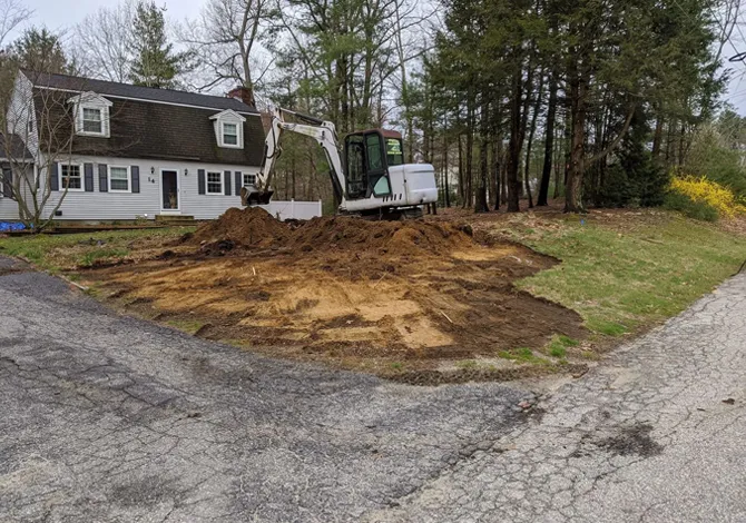Excavation work in front yard of residential home using mini excavator in New Hampshire