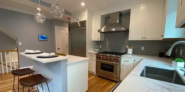 A kitchen with white cabinets , stainless steel appliances , a sink and a stove.