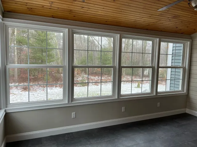 A sunroom with a lot of windows and a ceiling fan.
