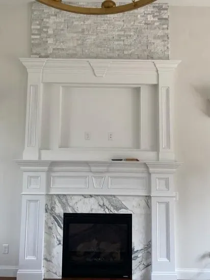 The recessed wall area prepared for a custom TV mantel installation above a white fireplace.