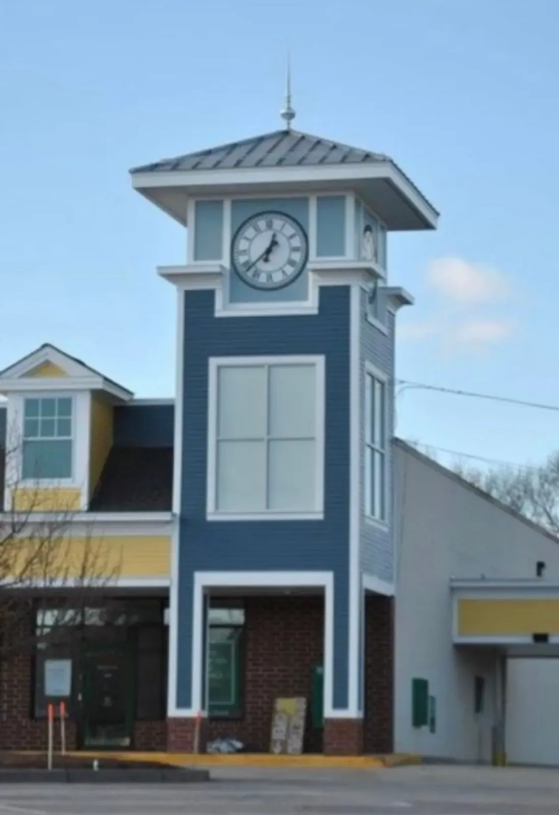 Clock tower on a blue-and-white building with a peaked roof under a clear sky