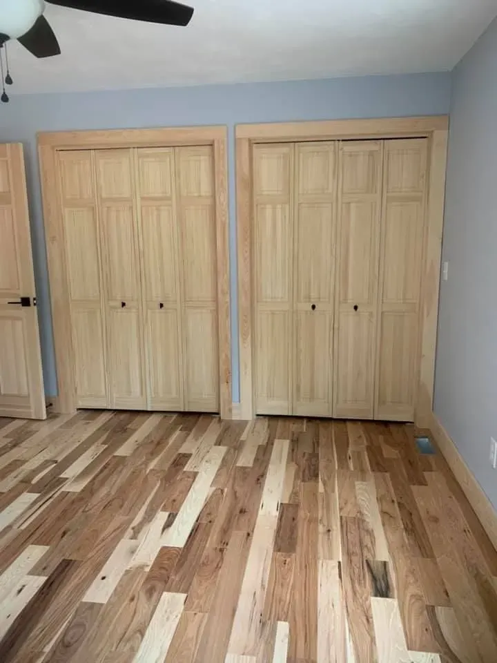 A bedroom with hardwood floors , closets , and a ceiling fan.